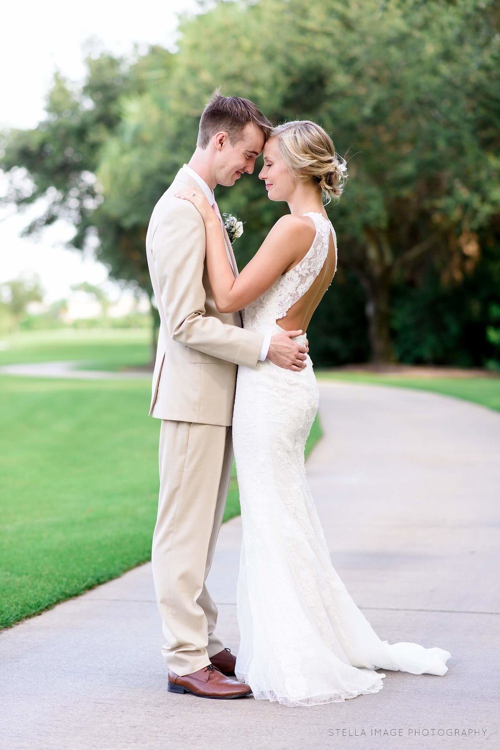 Bride and groom share a hug on the golf course at mayacoo lakes country club after wedding.